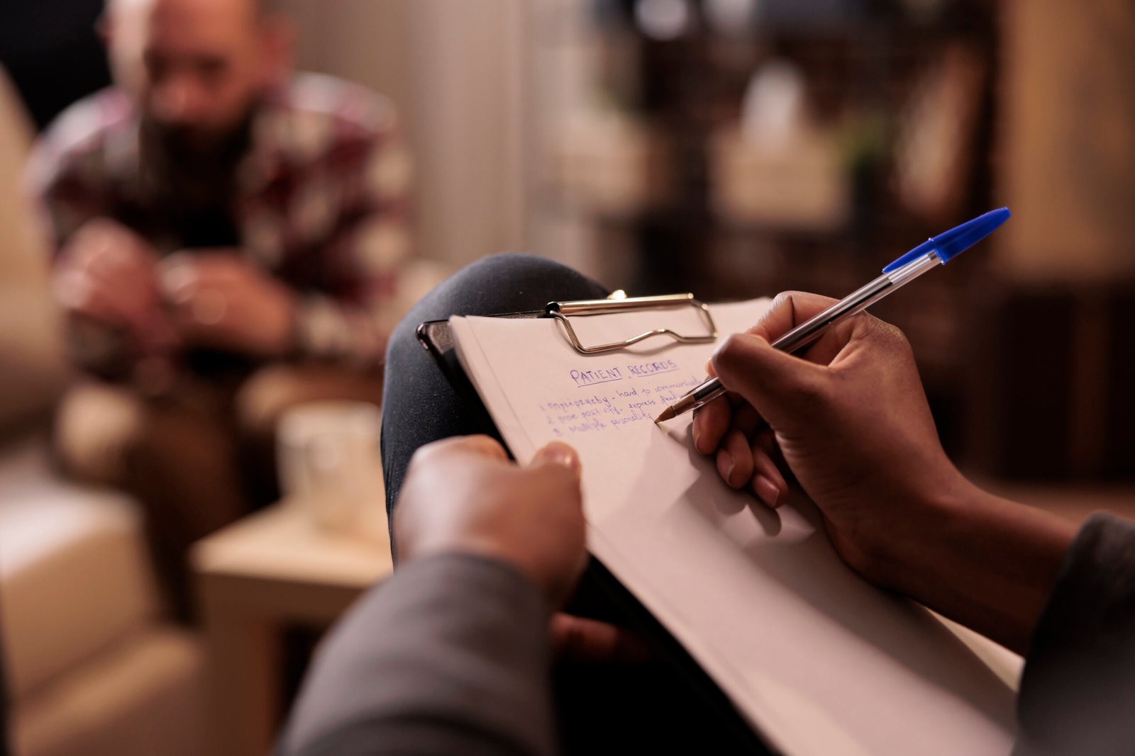 Psicólogo em atendimento terapêutico tomando notas durante uma sessão